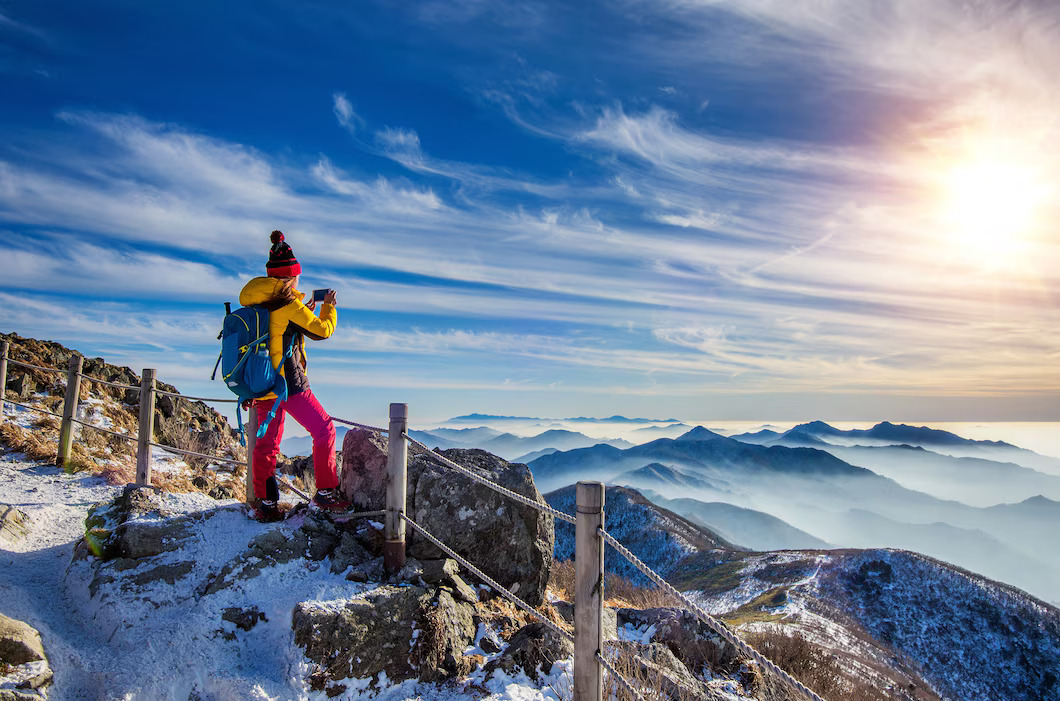 young-woman-hiker-taking-photo-with-smartphone-mountains-peak-winter_335224-427